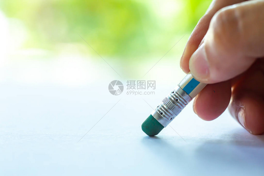女右手握彩色铅笔从白纸上删除的绿色橡胶散景绿色花园背景笔记本特写和微距拍摄选择焦点通图片