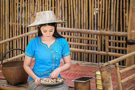 穿着蓝色传统泰国式服装的女孩正在收集蘑菇背景图片