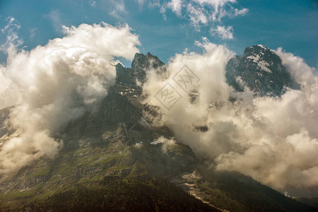 瑞士落基山脉的丛林山峰上的白雪和云层的图片