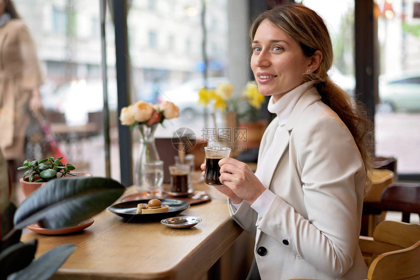 白套房的年轻金发美女在一家餐厅喝阿拉伯咖啡图片