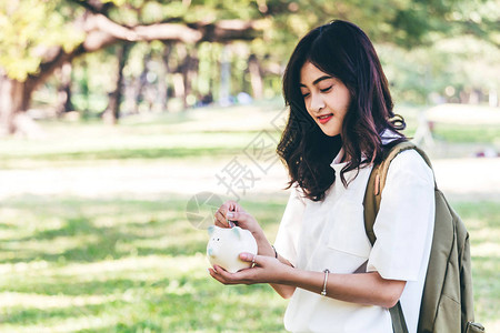 妇女手把硬币放进小猪银行储图片