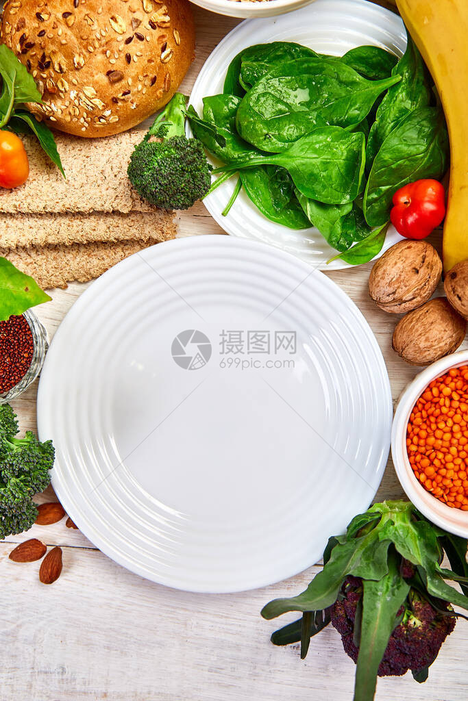 在空盘周围的白色木质背景上选择富含纤维的食物图片