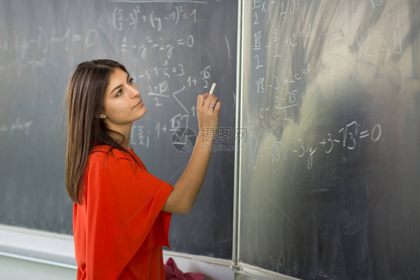 漂亮的年轻大学生年轻教师在数学课时在黑板图片