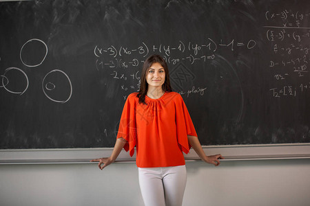 漂亮的年轻大学生年轻教师在数学课时在黑板图片