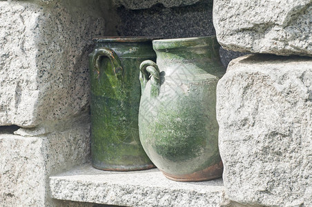 石墙花园壁龛特写中的空绿色陶瓷罐图片