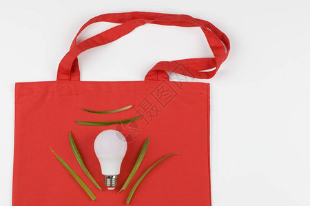 白色背景的生态红色天然袋上带有回收标志的灯泡生态和绿色能源的概念复图片