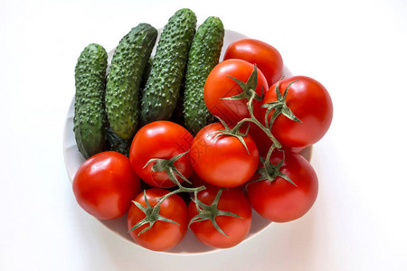 新鲜蔬菜西红柿和黄瓜在盘子上白图片
