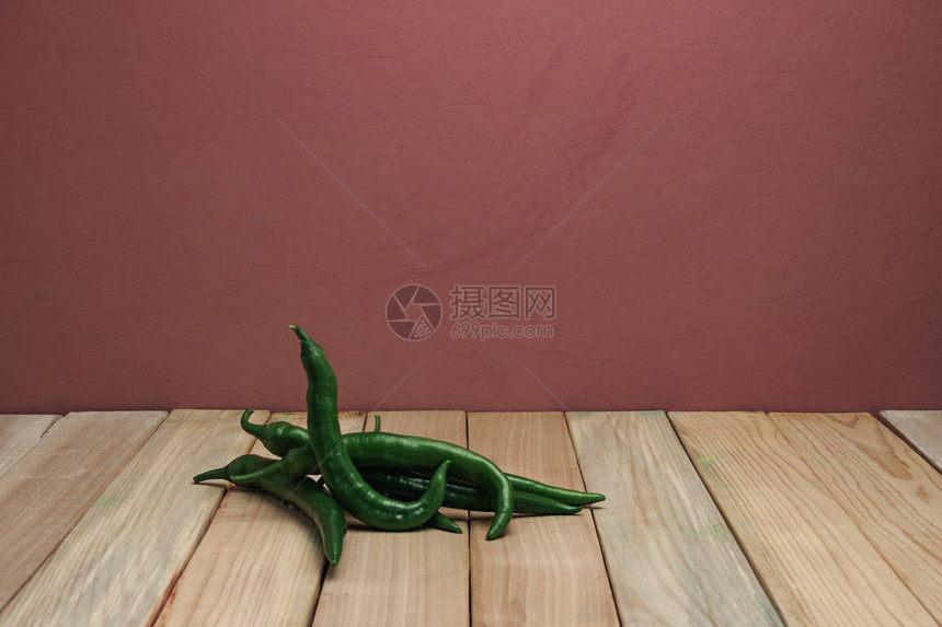 美丽的新鲜青椒在木桌和红墙背景上图片