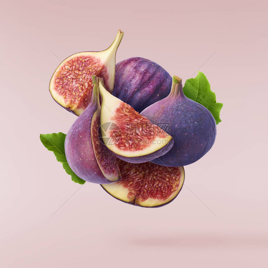 在空气中飞行新鲜的成熟整体切开在粉色糊面背景上隔离的Figs图片