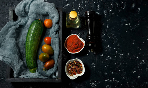深色背景上的蔬菜深色纹理表面上的香料油西葫芦番茄桃子从上面查图片