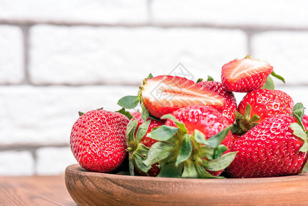 木桌上碗里的新鲜大草莓图片