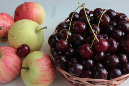 成熟的樱桃放在碗里苹果放在木桌上图片