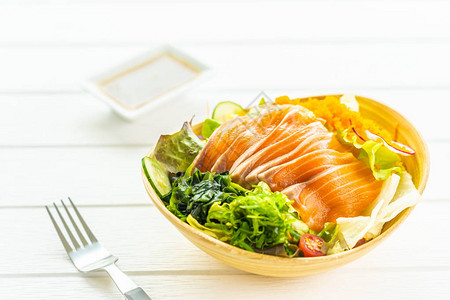 生鲜三文鱼肉生鱼片配蔬菜沙拉和酱汁图片
