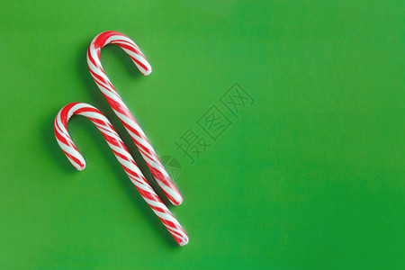 圣诞红背景两根圣诞红甘蔗和白甘蔗在纸质绿纸背景上背景
