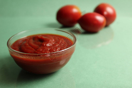背景中平底锅中的红番茄酱是绿色背景中的蔬菜红番茄图片