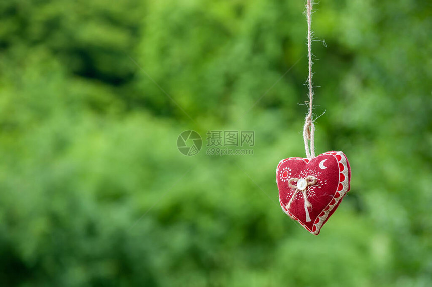 孤立的手工棉织物心挂在绿草背景的韧皮绳上挂在晾衣绳上的红色织物心夏季婚礼主题爱和图片