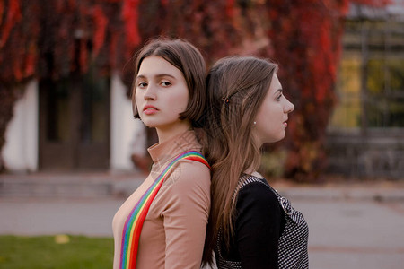 可爱的女孩背靠站着在秋天公园的悲伤美丽的学生年轻女在图片