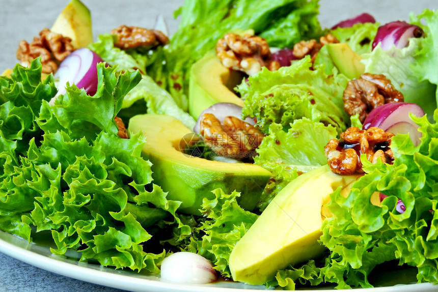 绿色沙拉配鳄梨蓝洋葱和核桃健康营养沙拉配鳄梨素食沙拉配蔬菜和鳄梨在盘子上图片