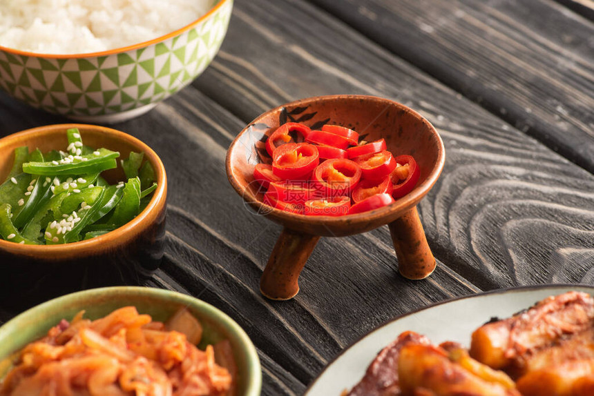青椒靠近米饭辣椒和韩国配菜在木质表面图片