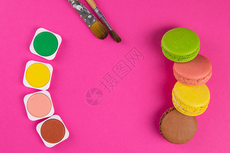 粉红背景的玛卡龙和画笔的颜色旁边是用于绘画的图片