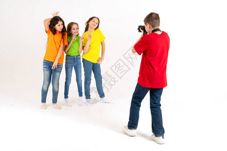 一位男孩摄影师在工作室里为三个身穿明亮T恤白色背景的可爱女孩拍照年轻的背景图片