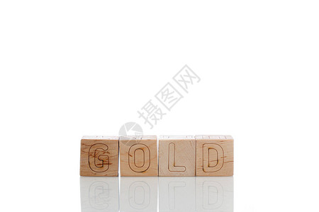 白色背景上带有金色字母的木制立方体特写图片