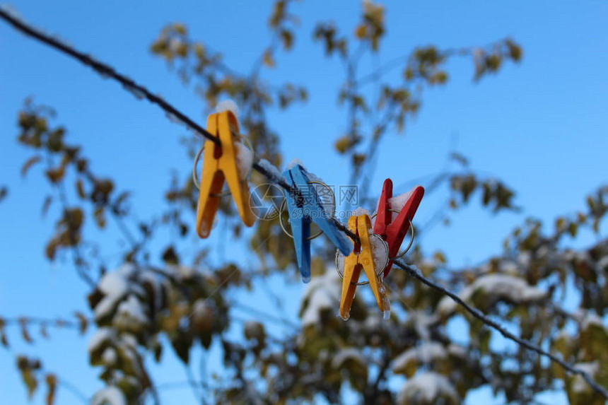 用于在寒冷的秋天在绳子上晒衣服的晾衣夹照片彩色晾衣夹它们系在院子街道上的晾衣绳上对着美丽图片