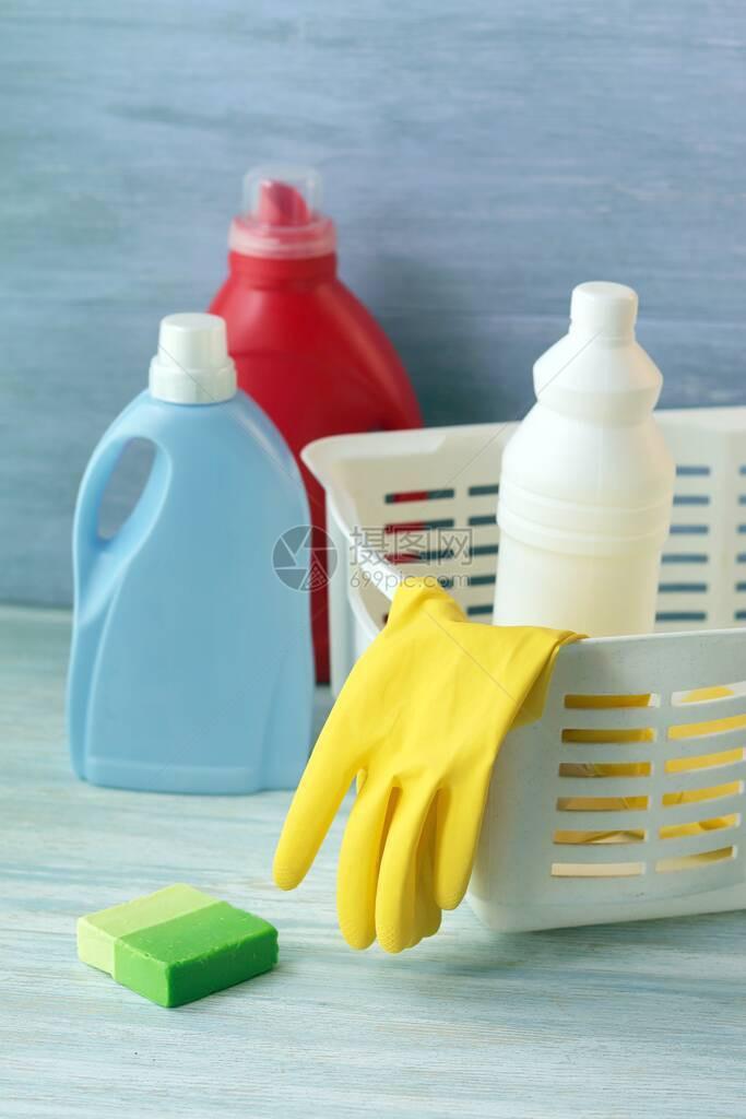 塑料瓶中的液体洗涤剂用橡胶手套在木制桌子上打图片