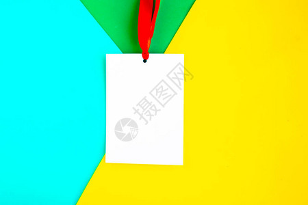 在几何绿色和黄色背景上贴有红丝带的白色模型徽章复制文本空间图片