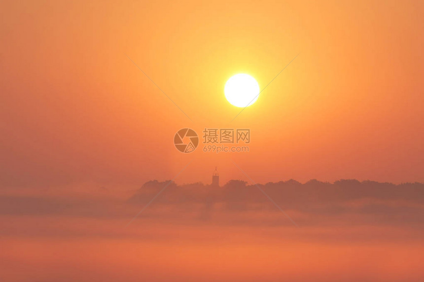 黄色太阳升起在朦胧的风景图片