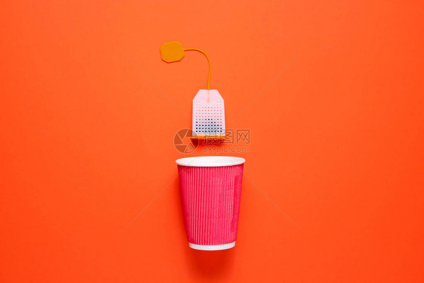 橙色背景的纸板茶杯和茶包顶视图极简主义图片