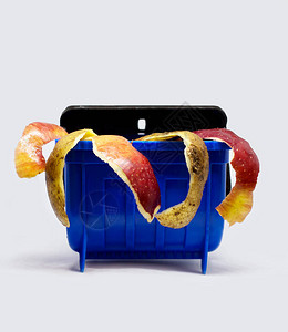 有机食品垃圾概念塑料蓝色玩具垃圾箱中的马铃薯和苹果在孤立背景下剥图片