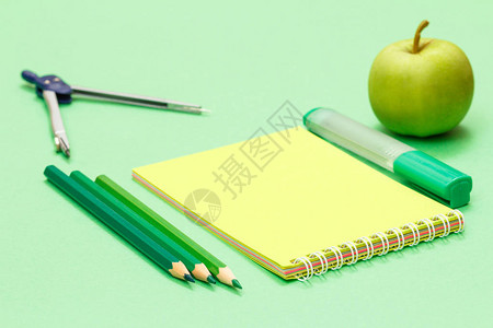 指南针彩色铅笔记本毡笔和绿色背景上的苹果回到学校的概念学校图片