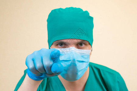 医生身着绿色防护服蓝色手套和蓝面罩图片