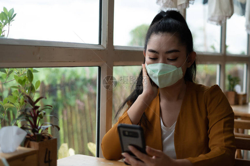 亚洲年轻女坐在咖啡厅戴上医用口罩图片