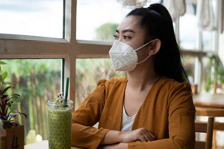年轻的亚洲女坐着戴上医用口罩图片