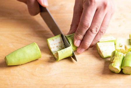 手拿菜刀在木板上切青茄子做饭图片