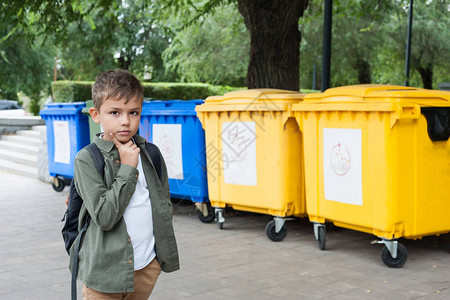 一个欧洲长相的男孩站在水箱前思考着要单独收集垃圾儿童图片