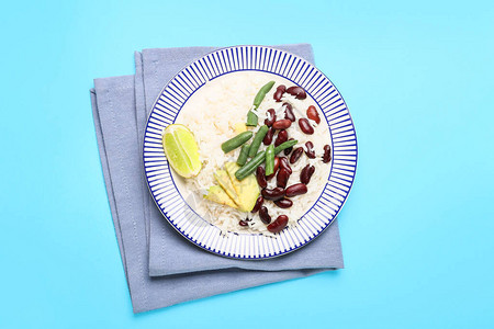 颜色背景上带有美味米饭豆类和鳄梨的盘子图片