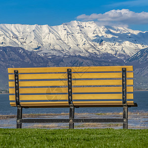 FrameSquare在阳光明媚的日子里俯瞰平静的湖面的空长凳的后视图从室外座位上还可以看到蓝天图片