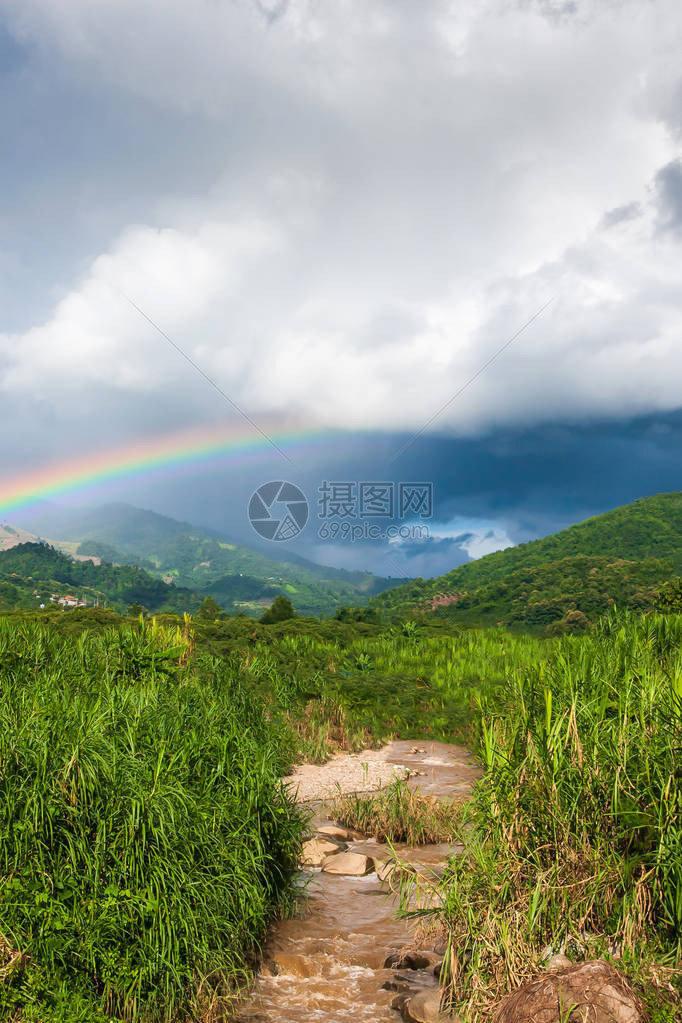 热带山谷上多彩的虹在雨中风景优美的图片