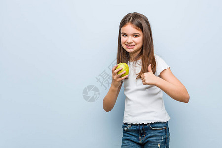 小caucasian女孩拿着绿色苹果微图片