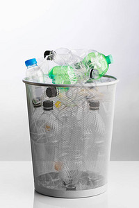 带有废弃塑料瓶的垃圾桶灰色背景图片