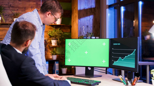 两个办公室同事在看绿色电脑屏幕图片