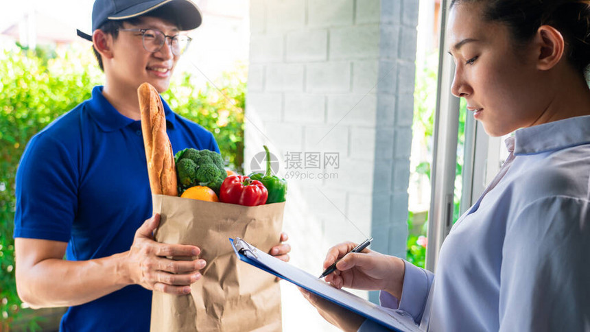 亚洲人在统一的食品蔬菜和蔬菜处理袋中送货到家门口的顾图片