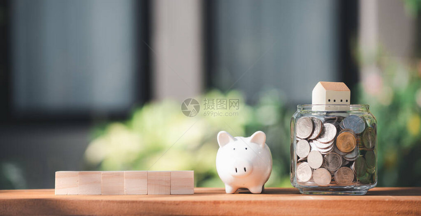 以自然绿草背景的硬币房屋木材立木和小猪银行模式图片
