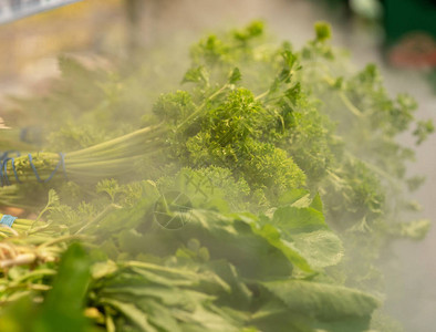超市柜台上用蒸汽浇灌的新鲜蔬菜束图片