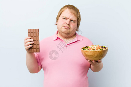 白人疯狂的金发胖男人在巧克力片和沙图片