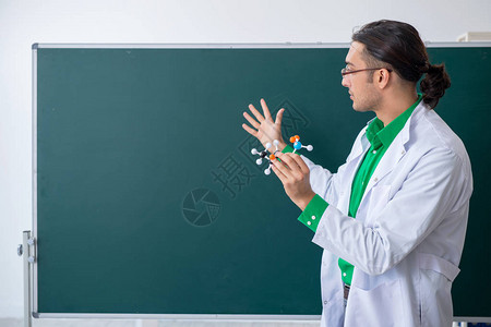 在黑板前的年轻男化学老师背景图片