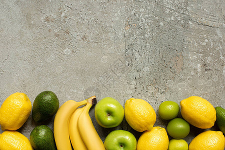 灰色混凝土表面的多彩香蕉苹果鳄梨石灰和图片